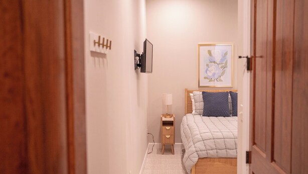 A bedroom with a bed, bedside table, lamp, and a framed picture on the wall.