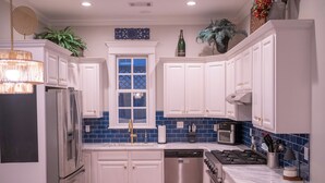 A modern kitchen with white cabinets, a stainless steel refrigerator, a dishwasher, a gas stove, and a microwave.