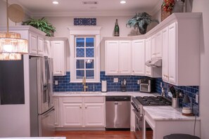 A modern kitchen with white cabinets, a stainless steel refrigerator, a dishwasher, a gas stove, and a microwave. - 3 King Beds with En Suite Bathrooms and Private Shuttle to Square & Stadium (Oxford)