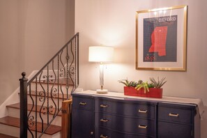 A staircase with a decorative railing, a wall-mounted lamp, a framed picture, and a plant in a red pot. - 3 King Beds with En Suite Bathrooms and Private Shuttle to Square & Stadium (Oxford)
