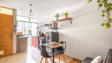 Une cuisine moderne avec un coin repas, une porte en bois et une plante suspendue.