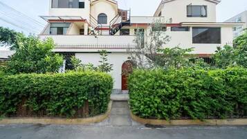 Un edificio residencial de dos pisos con una entrada central, una escalera y un pequeño porche.