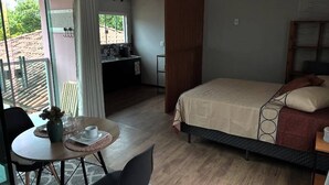 A bedroom with a bed, a desk, and a dining area with a table and chairs. - Guest house 700 meters from Moçambique beach and 500 meters from the state park. (Florianópolis)
