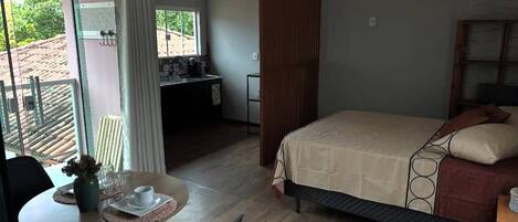 Een slaapkamer met een bed, een bureau en een zithoek met een tafel en stoelen.