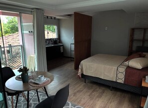 Ein Schlafzimmer mit einem Bett, einem Schreibtisch und einer Essecke mit Tisch und Stühlen.