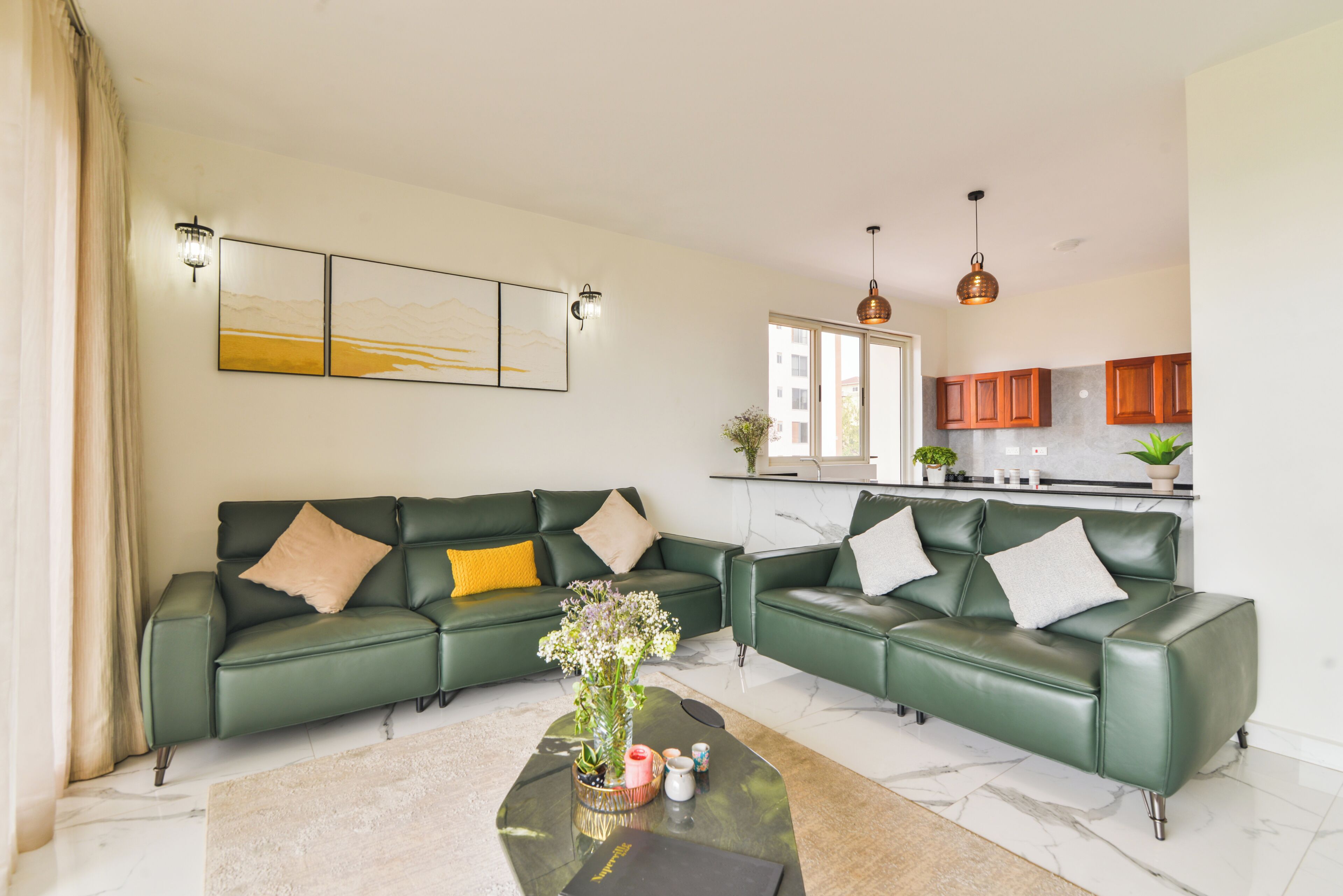 Una sala moderna con un sofá modular, una mesa de centro y una cocina al fondo.