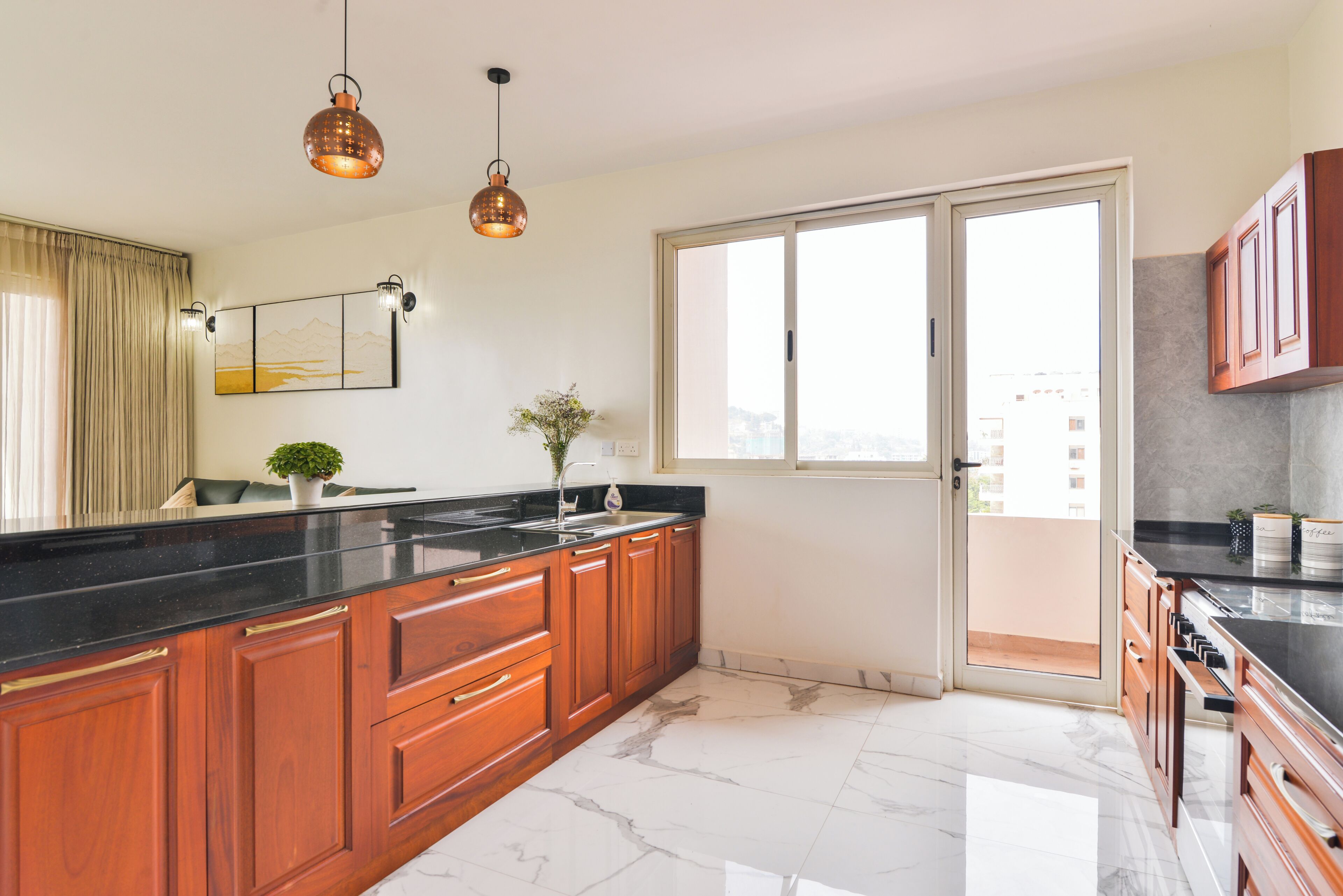 Una cocina moderna con piso de mármol, gabinetes de madera e iluminación colgante.