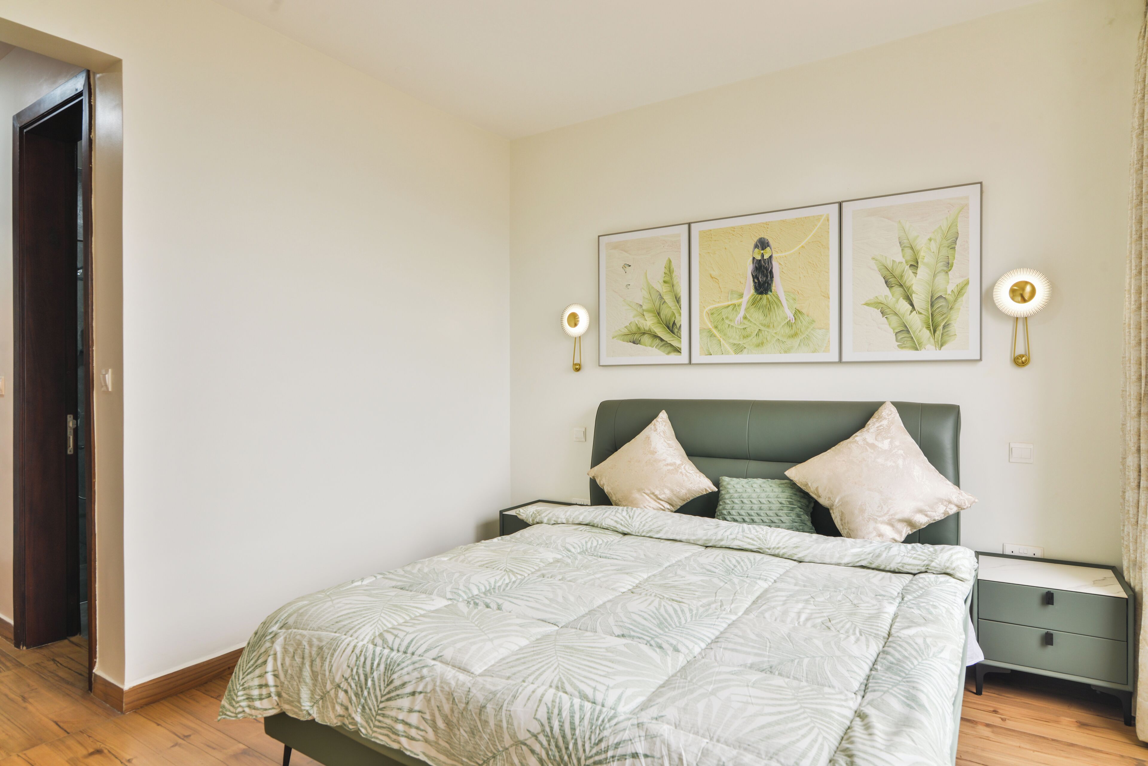 Un dormitorio con cama, dos lámparas de pared y tres láminas botánicas enmarcadas.