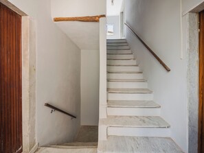 A staircase with white steps and a wooden handrail, leading to a room with a wooden door and a white wall. - Casa vacanze al teatro by Interhome (Carrara)