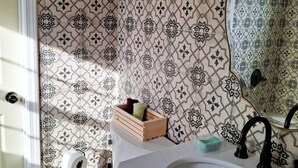 A bathroom with patterned tiles, a toilet, a sink with a mirror, and a wooden cabinet.