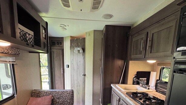 A compact RV kitchen with a stove, sink, and seating area. - MINI Camper -fully equipped stationary (Champlain)