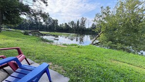A park bench with a metal frame and a backrest, positioned on a paved area with grass around. - MINI Camper -fully equipped stationary (Champlain)
