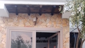 A person standing at a glass door entrance of a building with stone walls and a tiled floor. - Perfect 2-bedroom house in Chefchaouen for a relaxing stay (Chefchaouen)