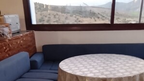 A room with a blue sofa, a round table with a patterned tablecloth, and a view through a window. - Perfect 2-bedroom house in Chefchaouen for a relaxing stay (Chefchaouen)