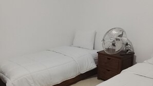 A room with two beds, a wooden nightstand with a fan, and a patterned rug. - Perfect 2-bedroom house in Chefchaouen for a relaxing stay (Chefchaouen)
