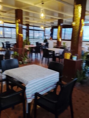 Ein Restaurantinneres mit Tischen, Stühlen, großen Fenstern und verzierten Säulen.