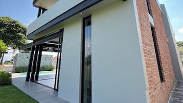 Un edificio moderno su due piani con tetto piatto, ampie finestre e una veranda coperta.