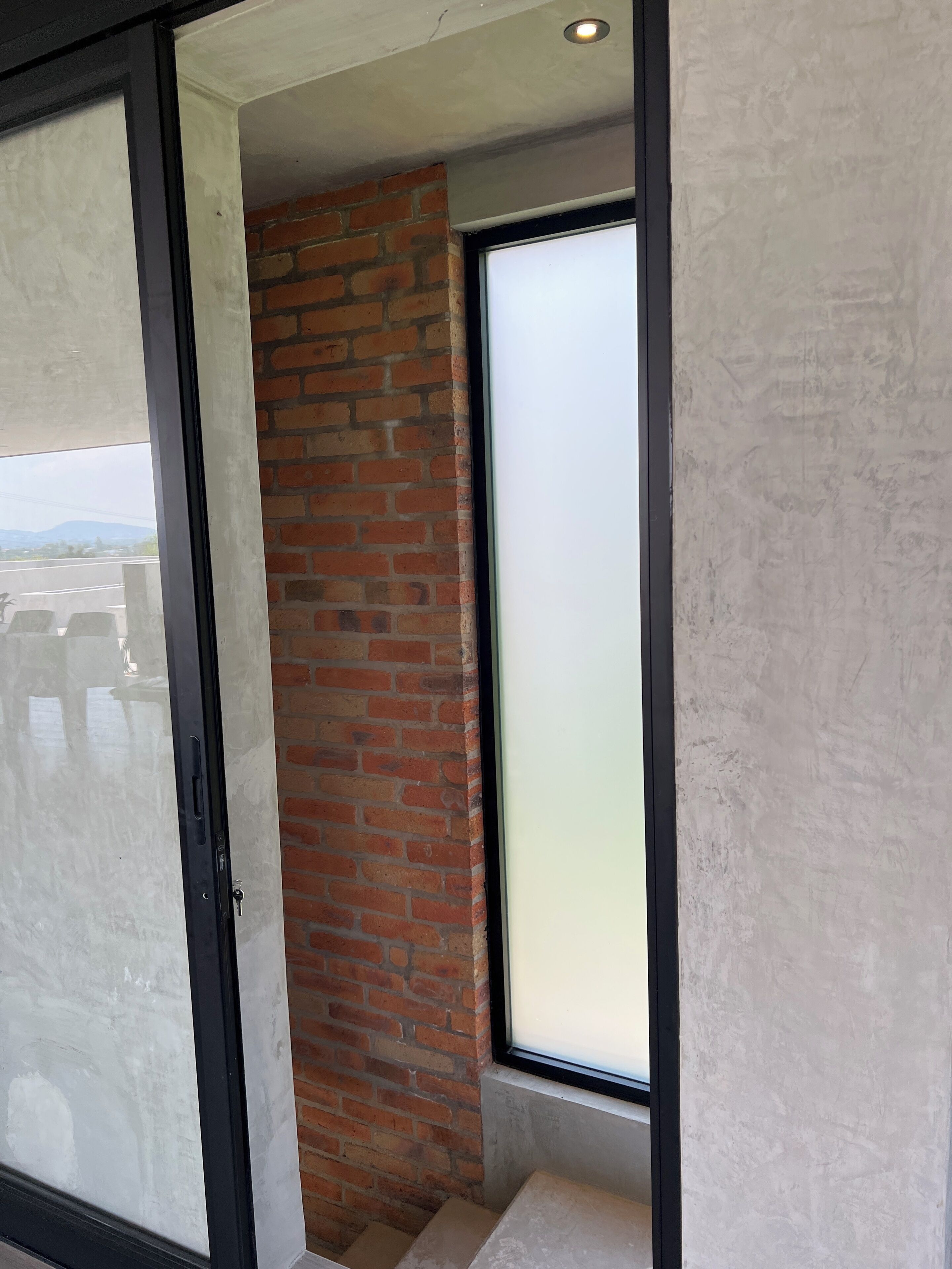 Een kamer met een glazen deur, een bakstenen muur en een groot raam.
