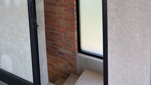 Une pièce dotée d’une porte en verre, d’un mur en briques et d’une grande fenêtre.