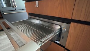 A kitchen with a built-in oven, a stainless steel range hood, and wooden cabinetry.