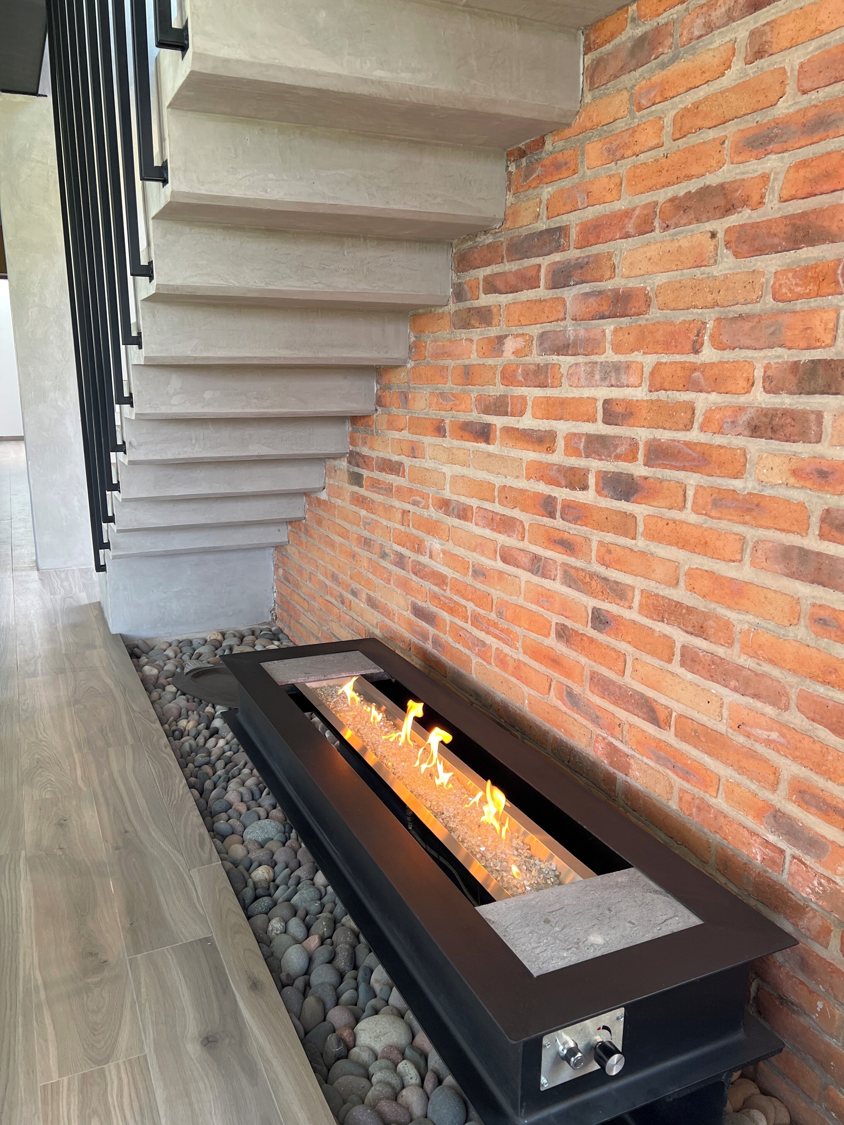 Ein modernes Interieur mit integriertem Kamin, einer Ziegelwand und Holzboden.