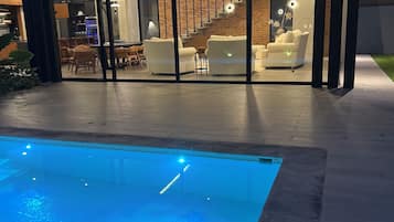 Una casa moderna con piscina, una zona relax all'aperto coperta e una scala che conduce a un piano superiore.
