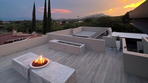 A rooftop terrace with a fire pit, seating areas, and a view of the surrounding landscape.