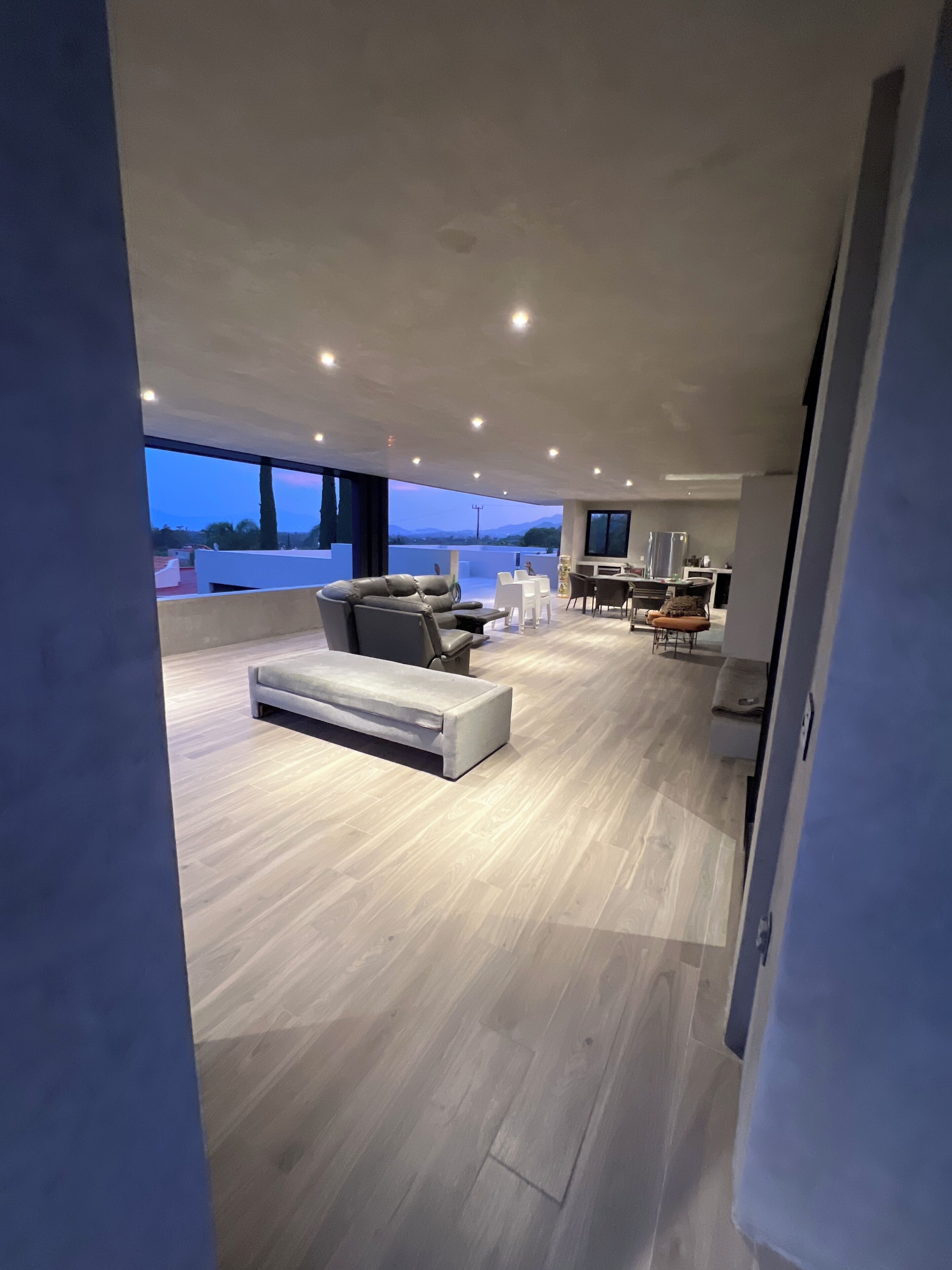 Un vaste espace de vie comprenant un canapé, un pouf et une table à manger.