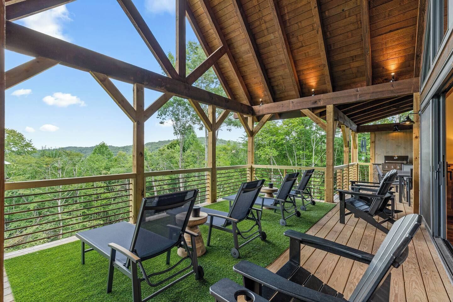 Un espacio al aire libre cubierto con una terraza de madera, asientos y vistas del paisaje circundante.