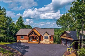 A two-story log cabin with a stone foundation, a front porch, and a garage. - Stunning Mountain Views | Hot Tub | Fireplaces | 3 Kings (Blue Ridge)