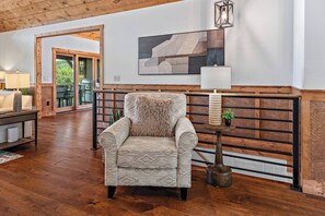 A cozy living room with a patterned armchair, a side table with a lamp, and a wooden wall panel. - Stunning Mountain Views/Hot Tub/Fireplaces /3 Kings (Blue Ridge)