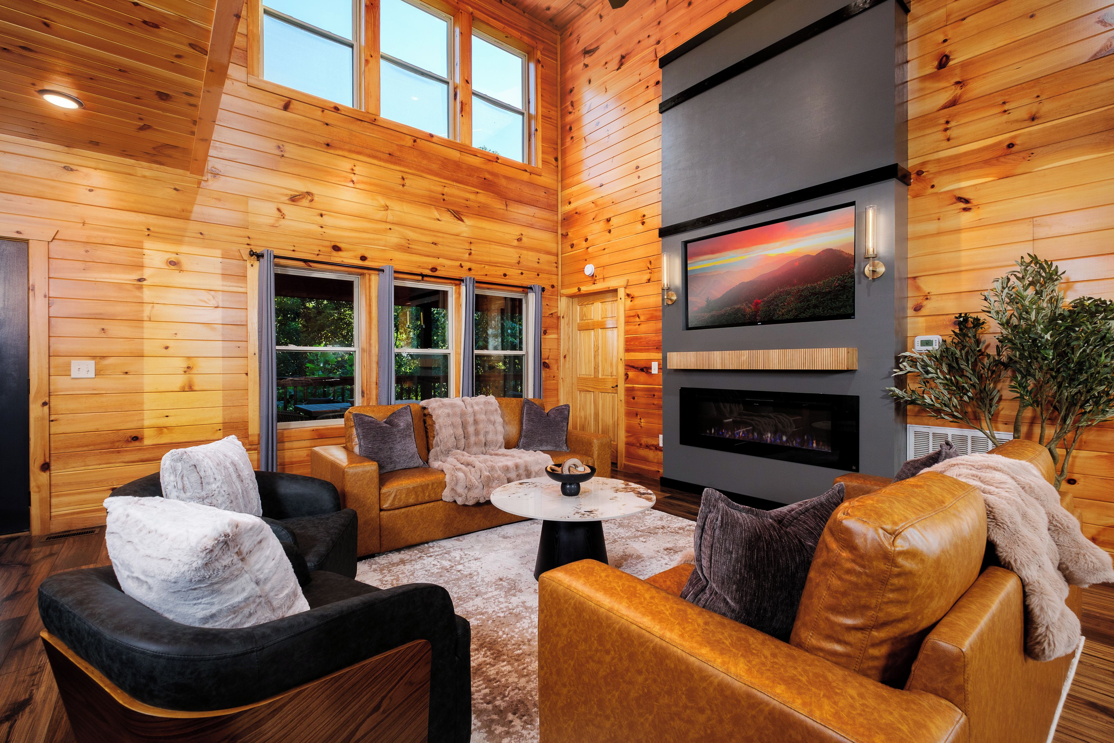 Interior acogedor de una cabaña de madera con chimenea, asientos cómodos y ventanas amplias.