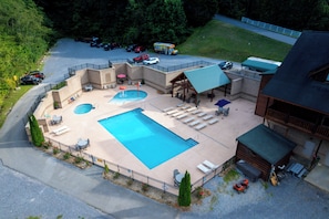 A resort with a large swimming pool, outdoor seating, and a covered area. - Newly Renovated Modern 4BR Cabin w/Indoor Pool ☆ Hot Tub ☆ Theater ☆Arcade Games (Sevierville)