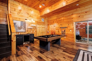A wooden interior with a pool table, cabinets, and a door leading to a balcony. - Newly Renovated Modern 4BR Cabin w/Indoor Pool ☆ Hot Tub ☆ Theater ☆Arcade Games (Sevierville)