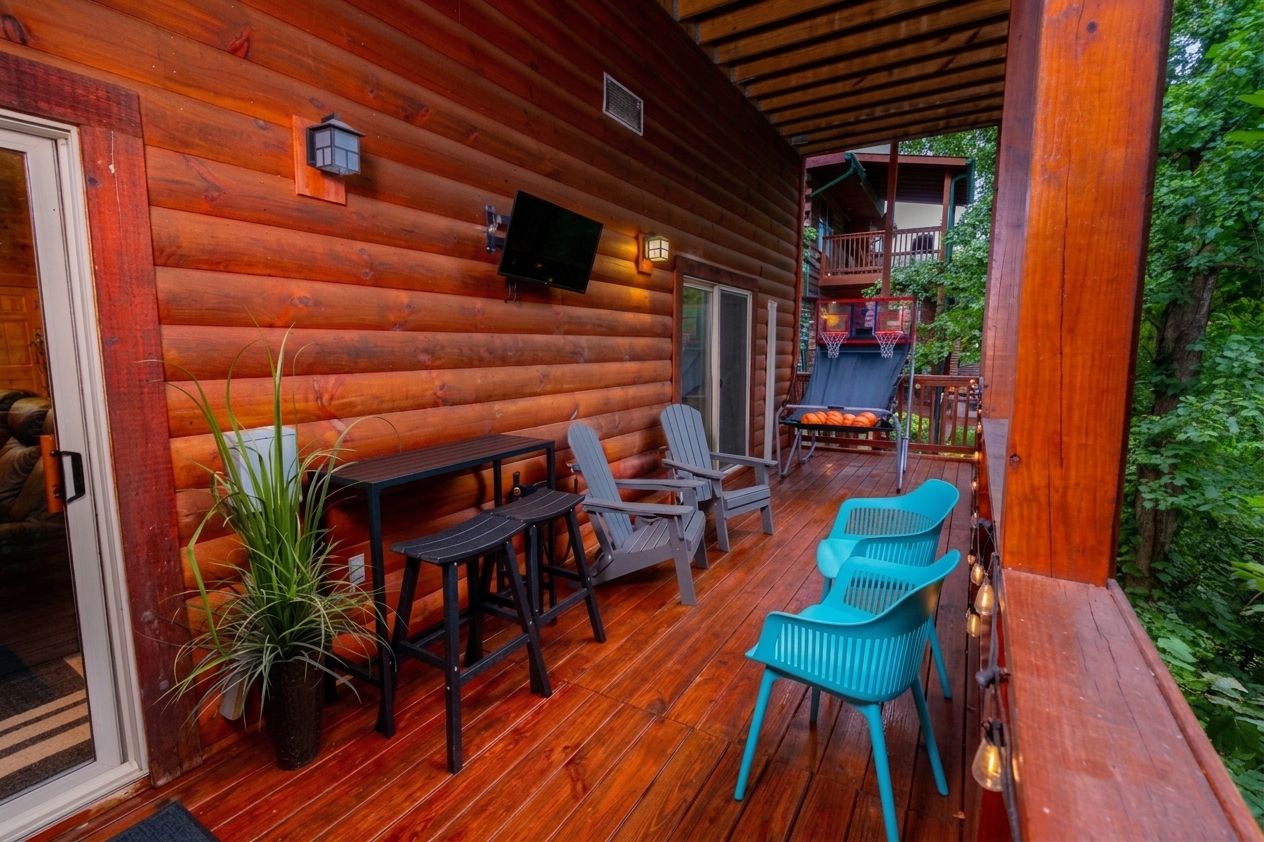 Une cabane en bois avec un porche, un espace salon extérieur et un panier de basket.