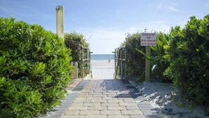 Un camino pavimentado que lleva a una playa, con un letrero que indica que los muebles del hotel deben ser llevados a la playa.