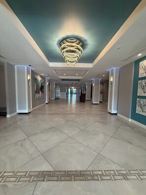 A hotel corridor with a modern chandelier, tiled flooring, and artwork on the walls. - Newly updated king studio perfect for honeymooners (Daytona Beach)