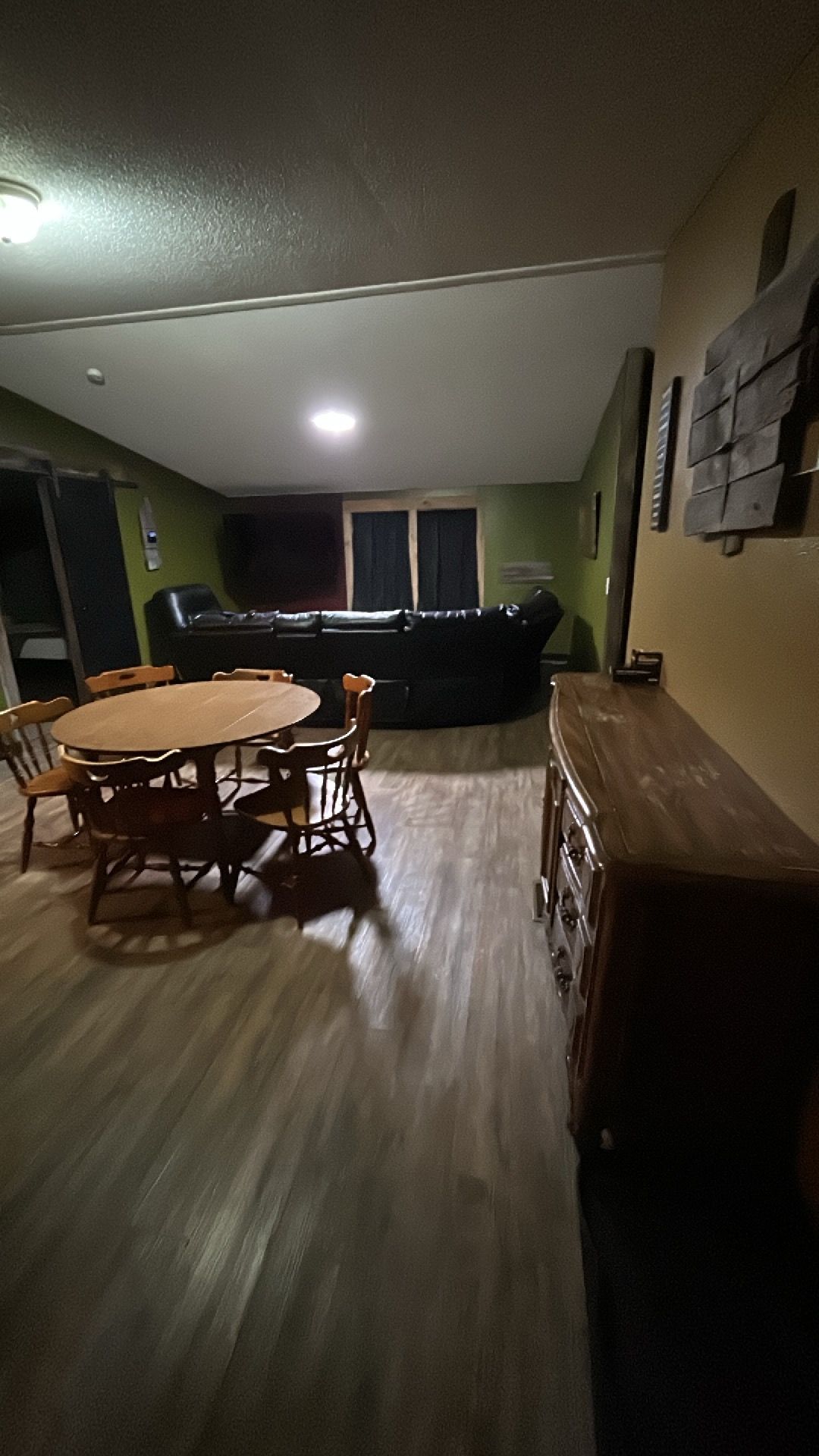 Uma sala de jantar com uma mesa redonda e cadeiras, um sofá e um armário de madeira.