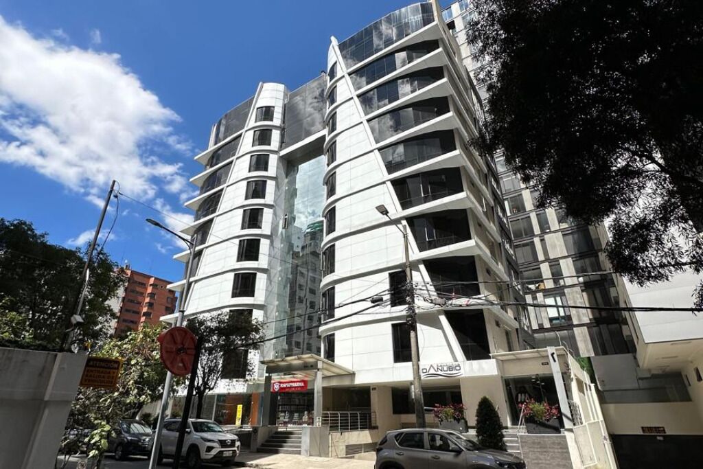A multi-story building with a modern architectural design, featuring balconies and large windows.
