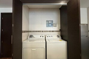 A laundry room with two front-loading washing machines and a small electrical panel on the wall. - Suite in La Carolina Area - Quito Ecuador (Quito)