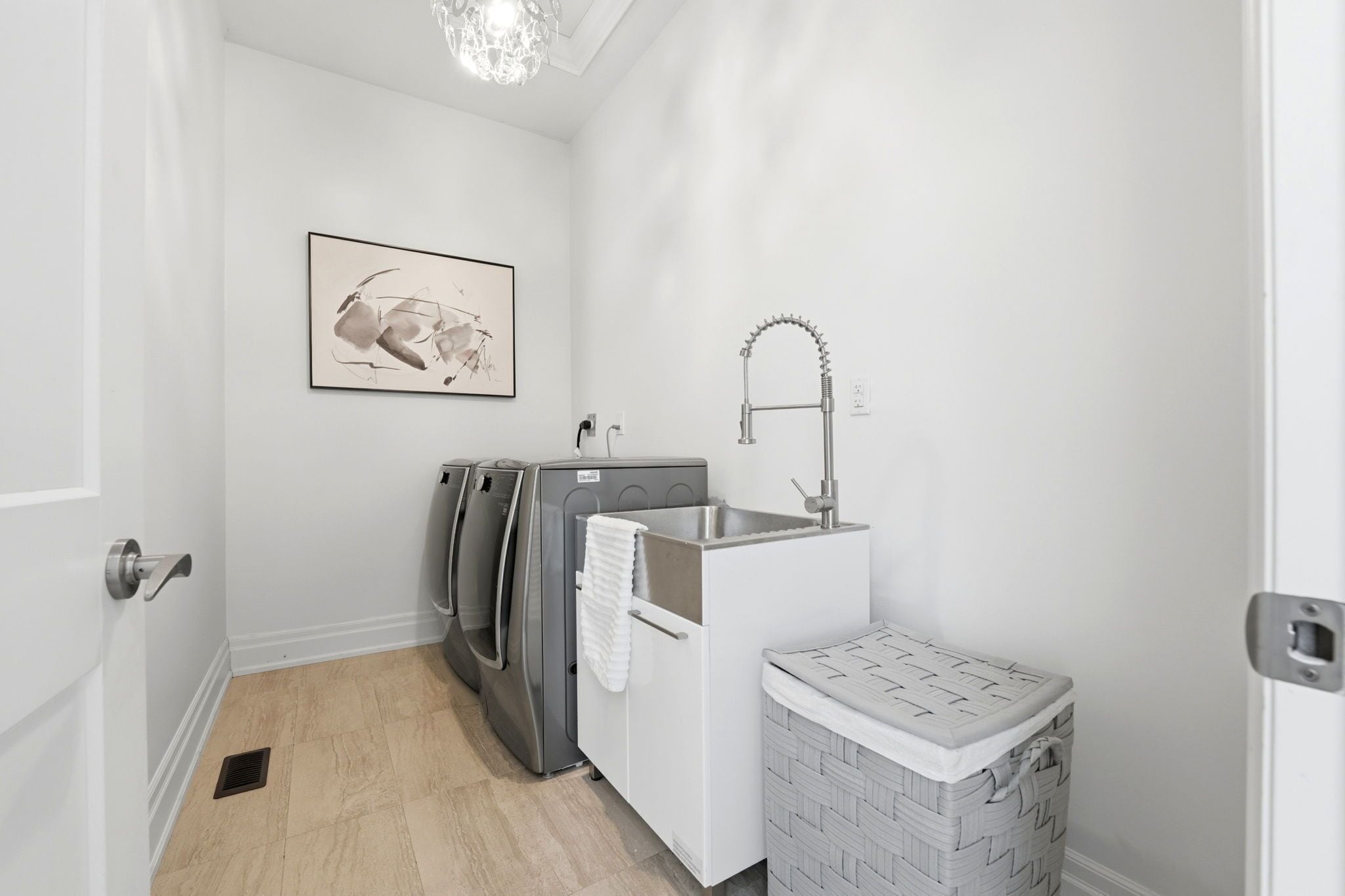 A compact laundry area with a washing machine, a sink, and a small storage bin.
