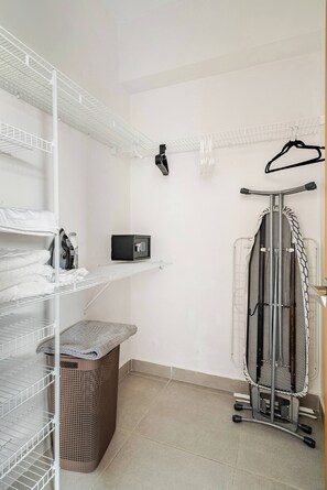 A laundry room with shelves, a washing machine, and an iron. - Step Into Elegance and Comfort (Santo Domingo)