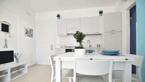 Uma cozinha moderna com armários brancos, uma mesa de jantar com cadeiras e um vaso com planta na mesa.