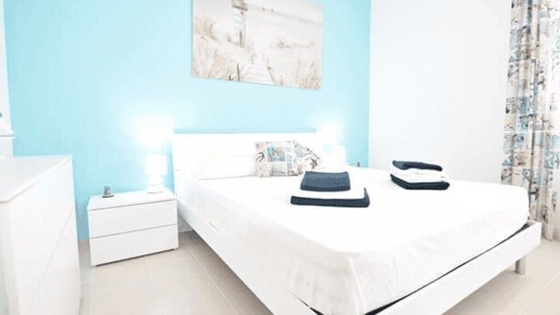 Um quarto com uma cama, mesas de cabeceira e um quadro na parede.