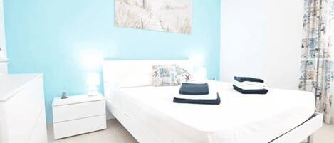 Un dormitorio con cama, mesitas de noche y un cuadro en la pared.