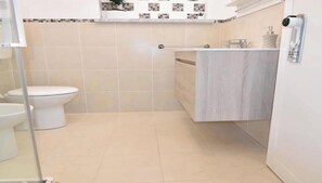 Ein Badezimmer mit Toilette, Duschbereich und Handtuchhalter.