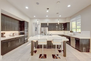Una cocina moderna con una isla central, electrodomésticos de acero inoxidable e iluminación colgante.