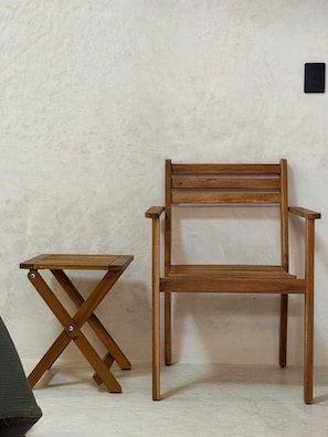 Una silla de madera y una mesita contra una pared lisa.