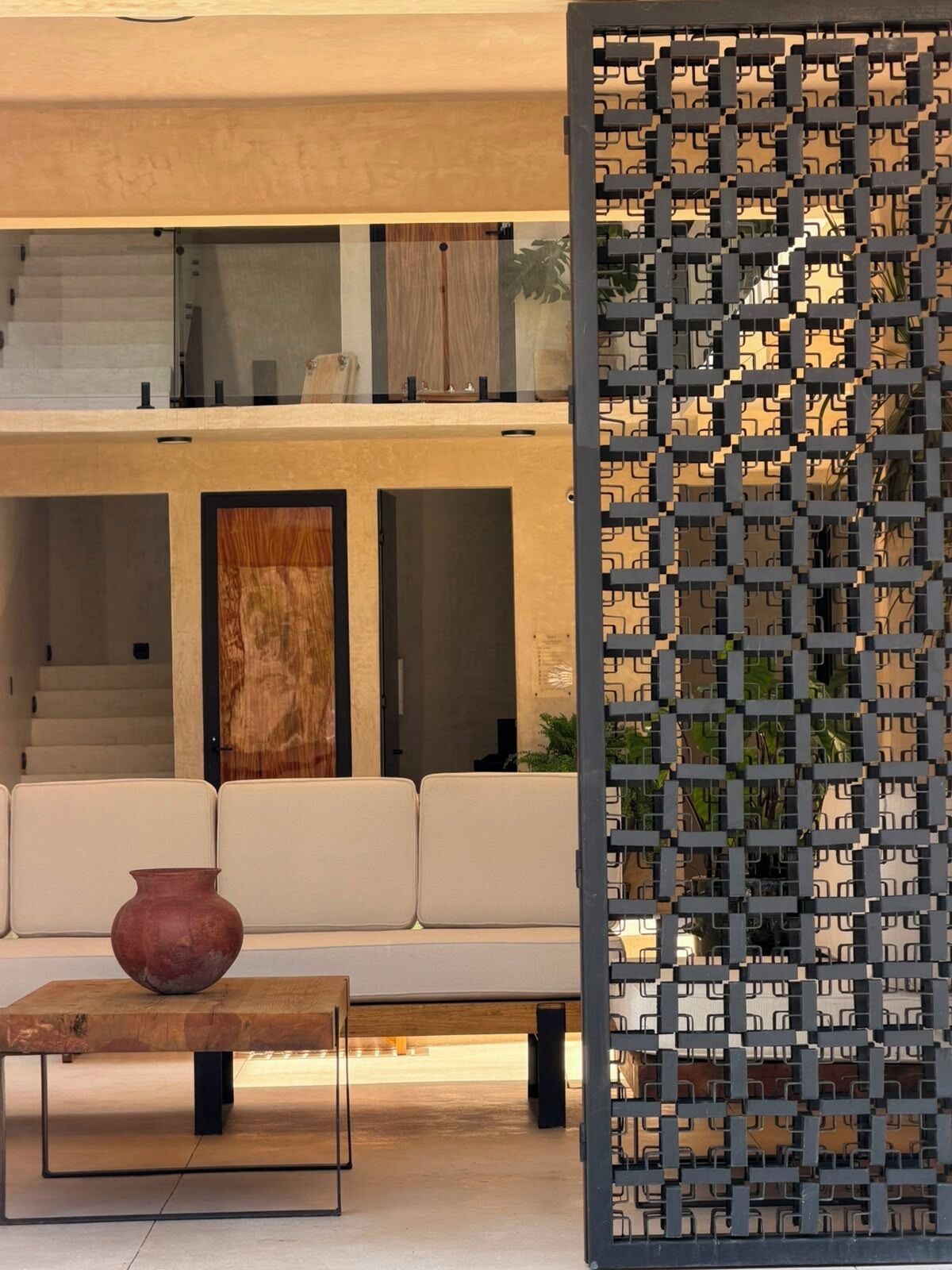 A modern interior with a sofa, a wooden table, and a decorative screen.