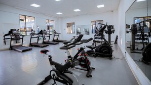 Un gimnasio con equipos de ejercicio variados, incluyendo cintas de correr, bicicletas estáticas y máquinas de pesas.